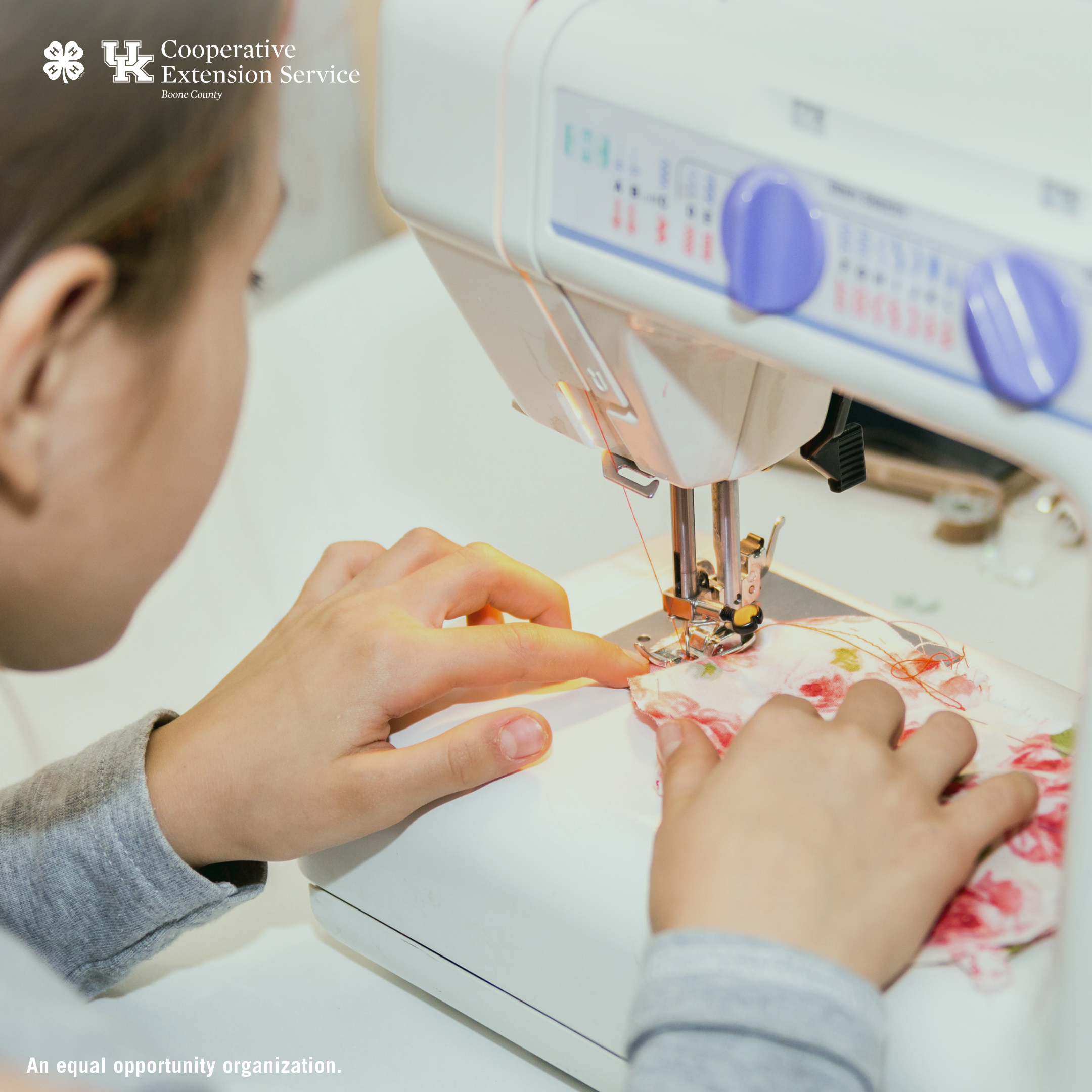 Close up image of a child sewing on a white sewing machine, angle is zoomed into the child's hands. 